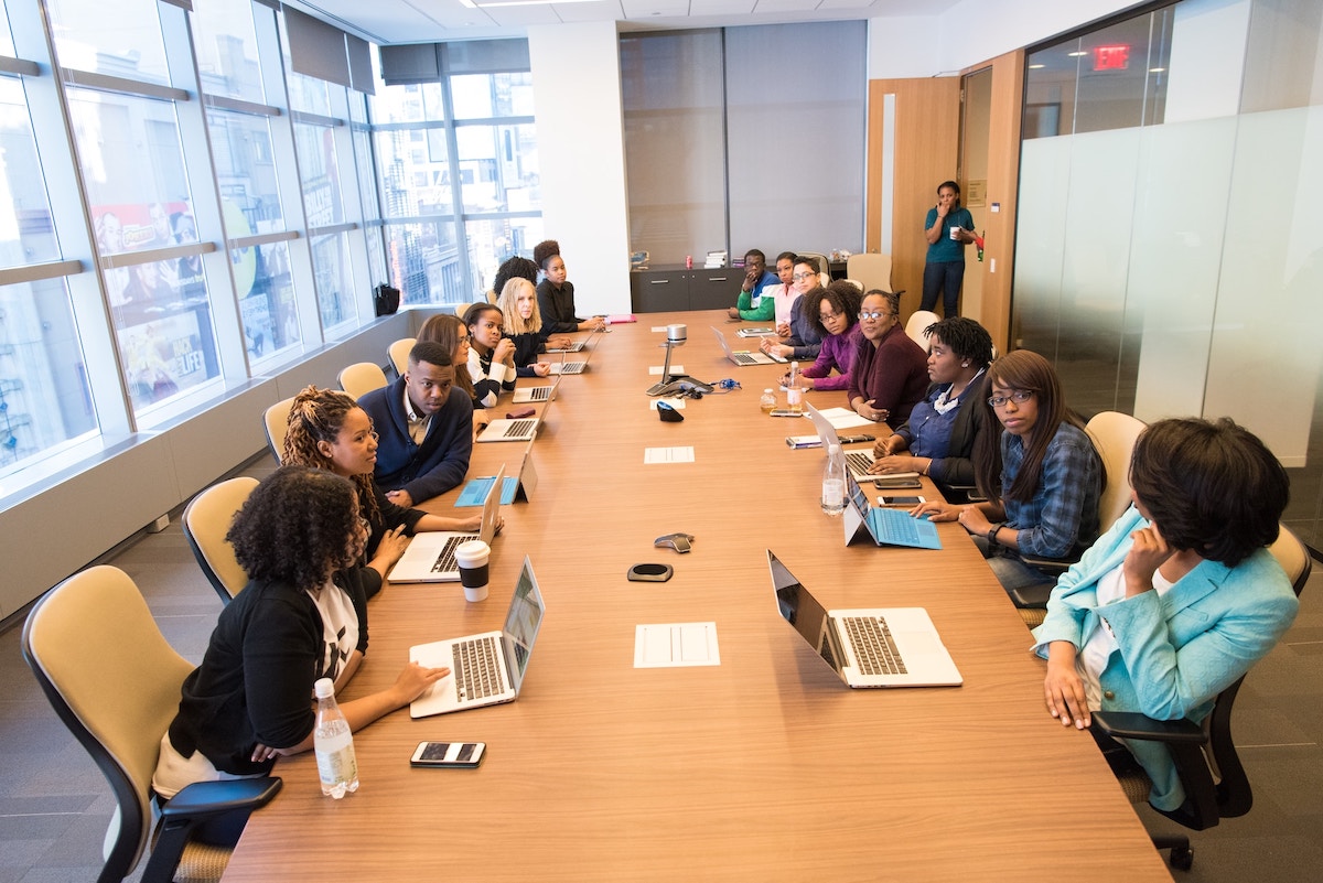 Many women around a high-rise conference room table deep in discussion