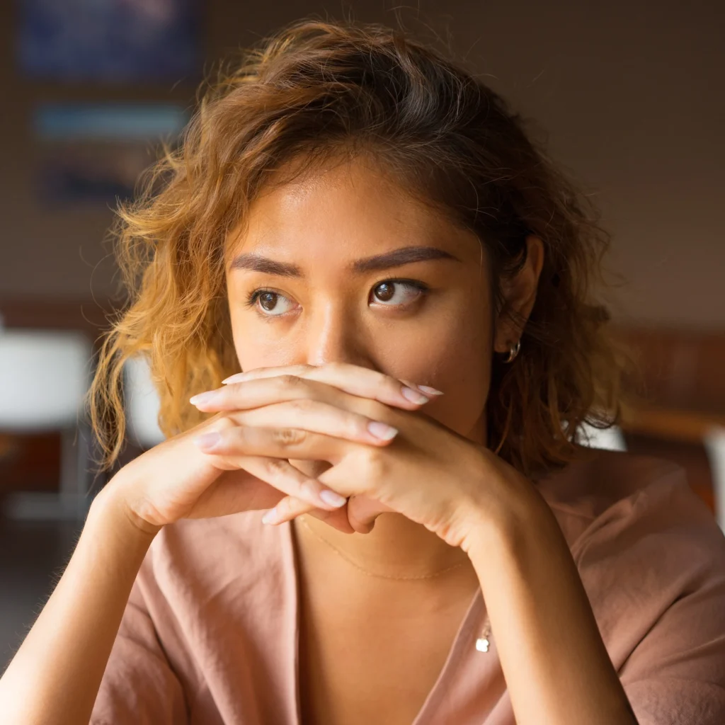 woman contemplating with her hands folded in front of her face